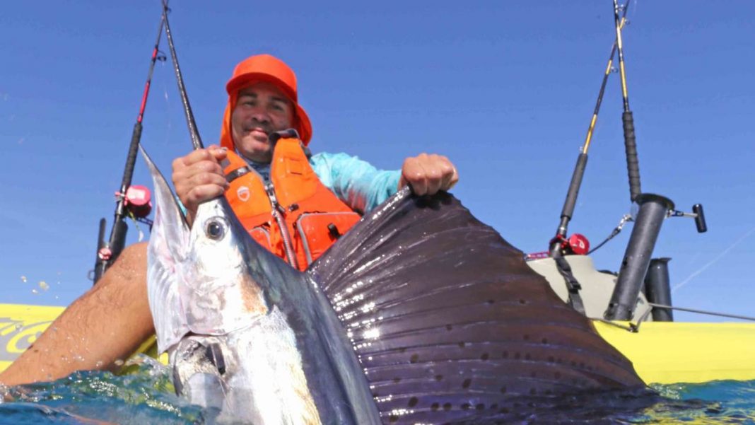 Kayak angler holds up a large swordfish.