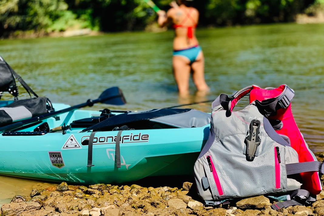 PFD leaning up against a fishing kayak pulled up on shore